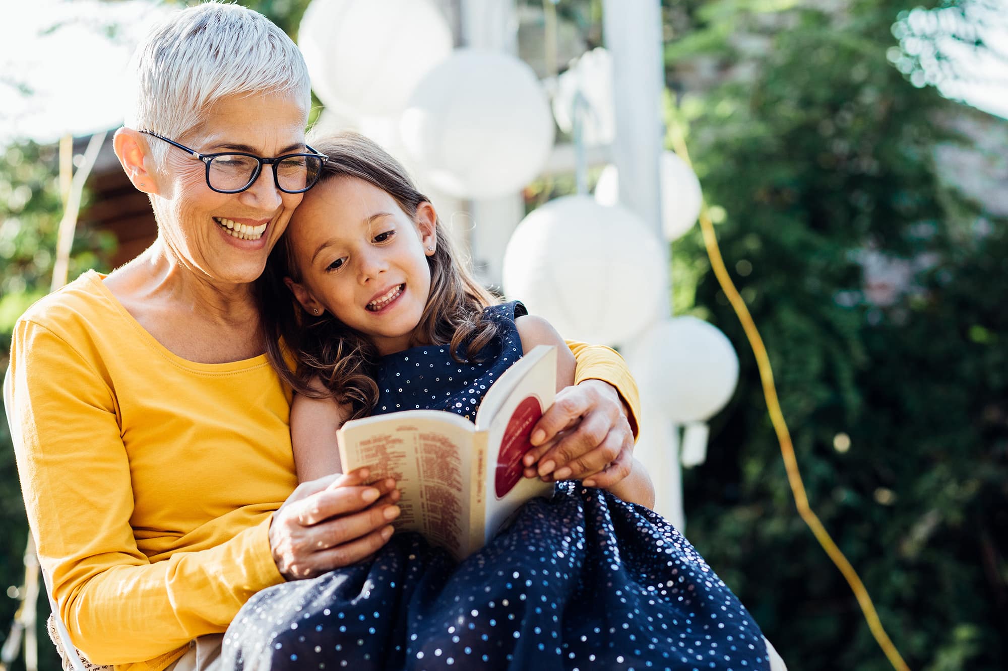 Senior woman reading a book to young granddaughter